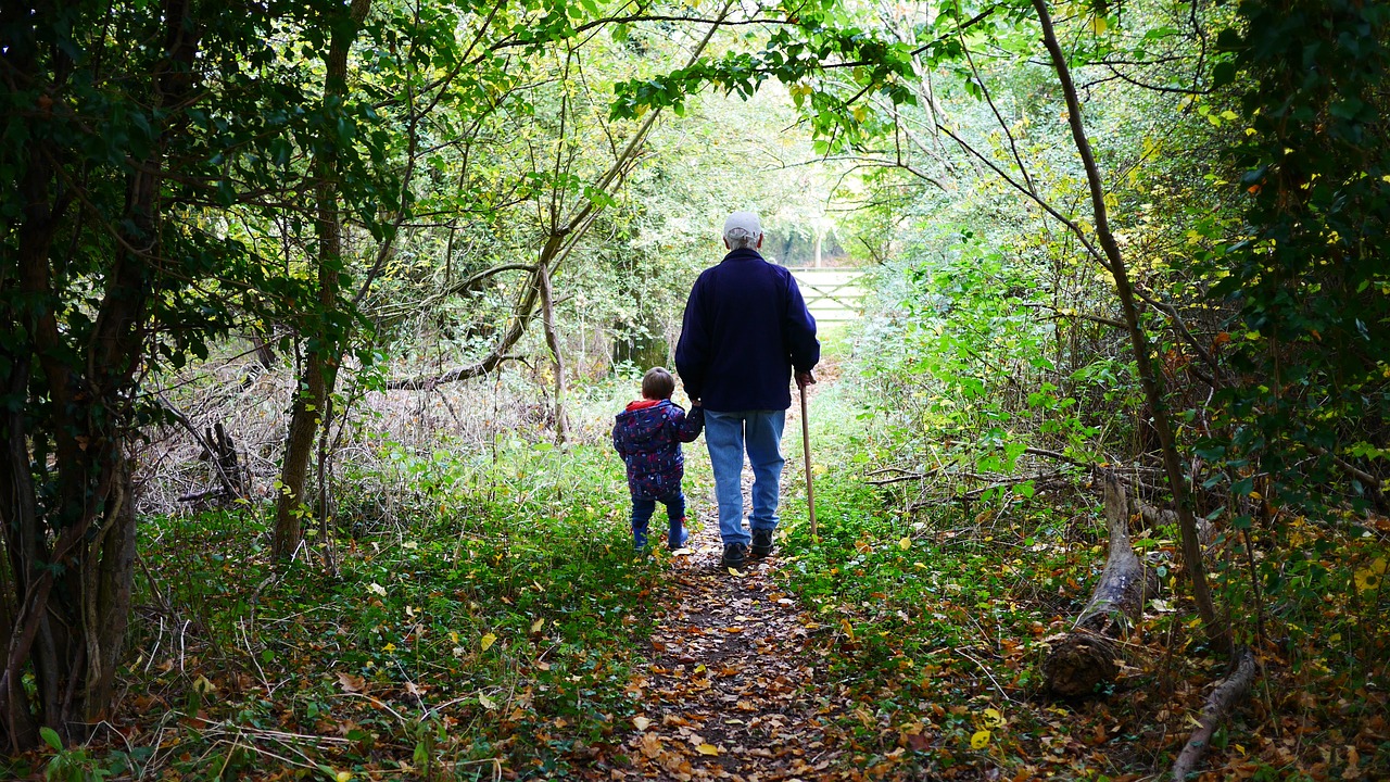 Grandparent walking with child on a path through the woods